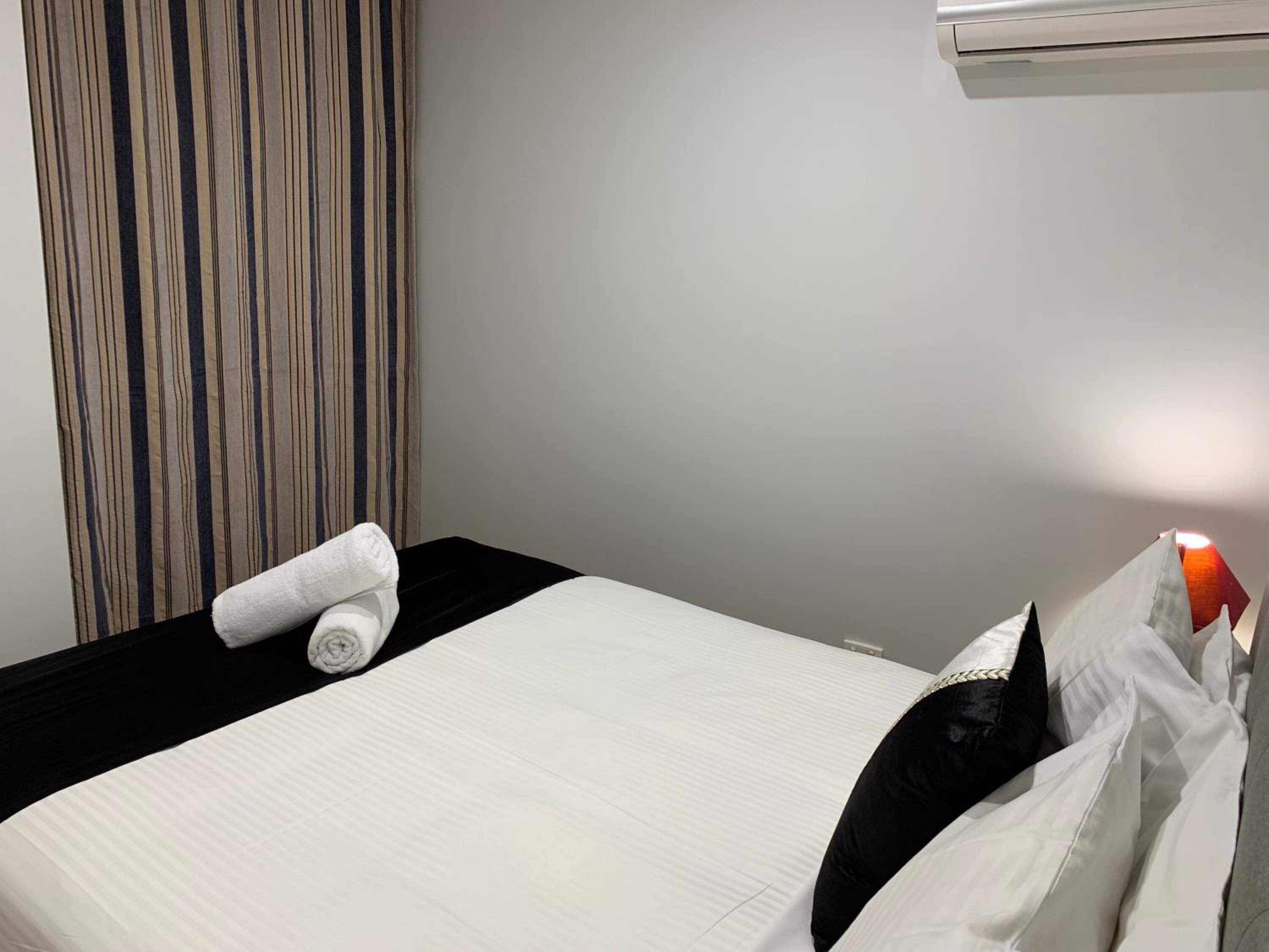 Ett hotellrum med en säng, en randig gardin och en luftkonditioneringsanläggning.