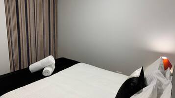 Ett hotellrum med en säng, en randig gardin och en luftkonditioneringsanläggning.