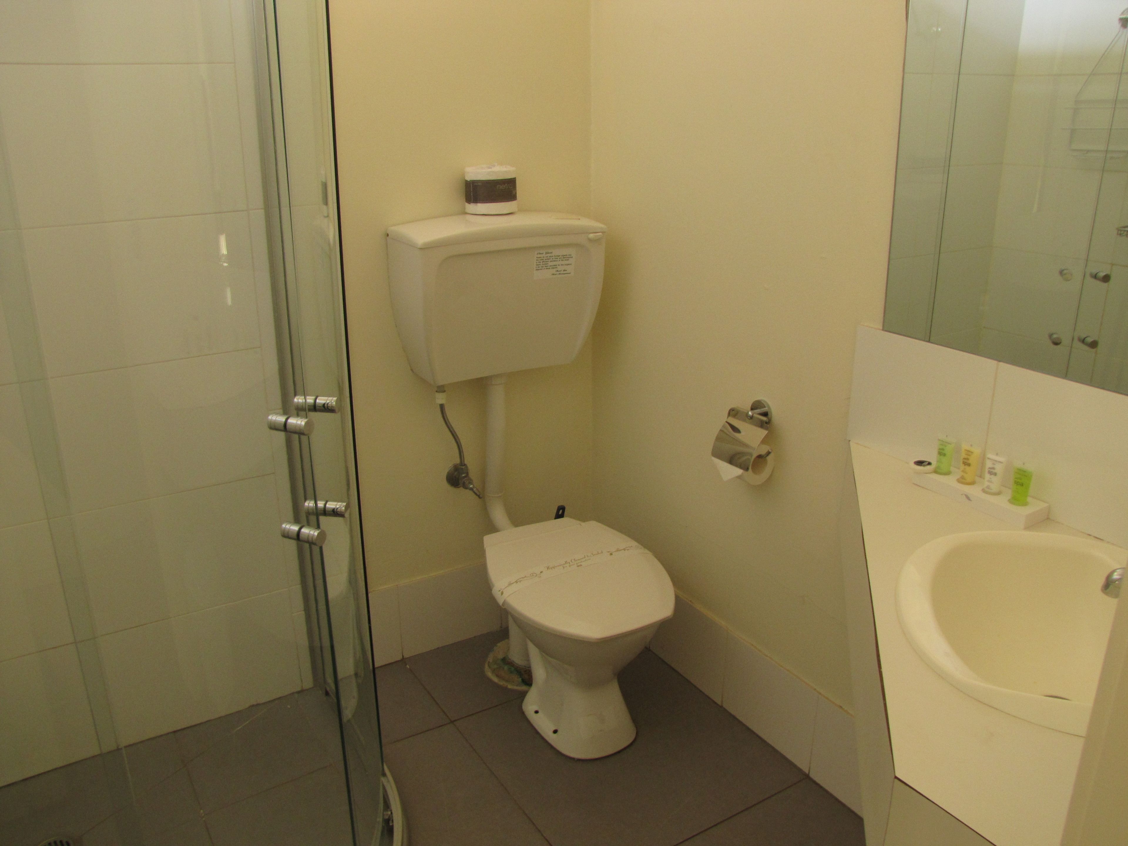 A bathroom with a toilet, a glass shower enclosure, and a sink.