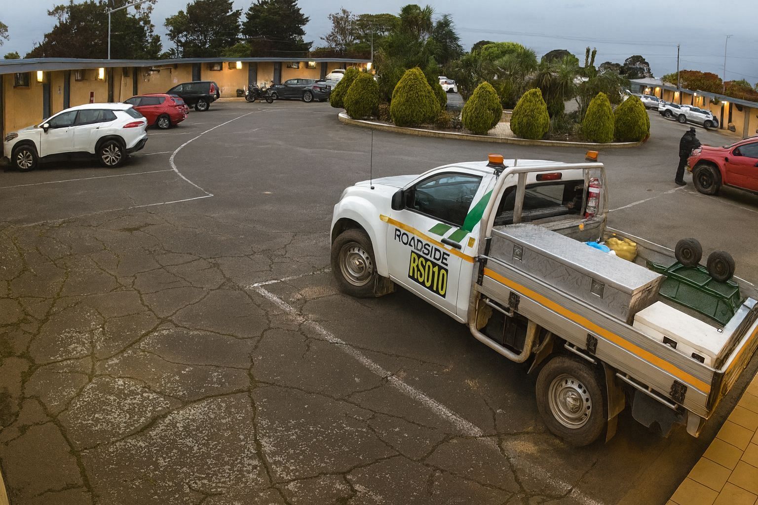A utility truck parked in a parking lot with a motel in the background.