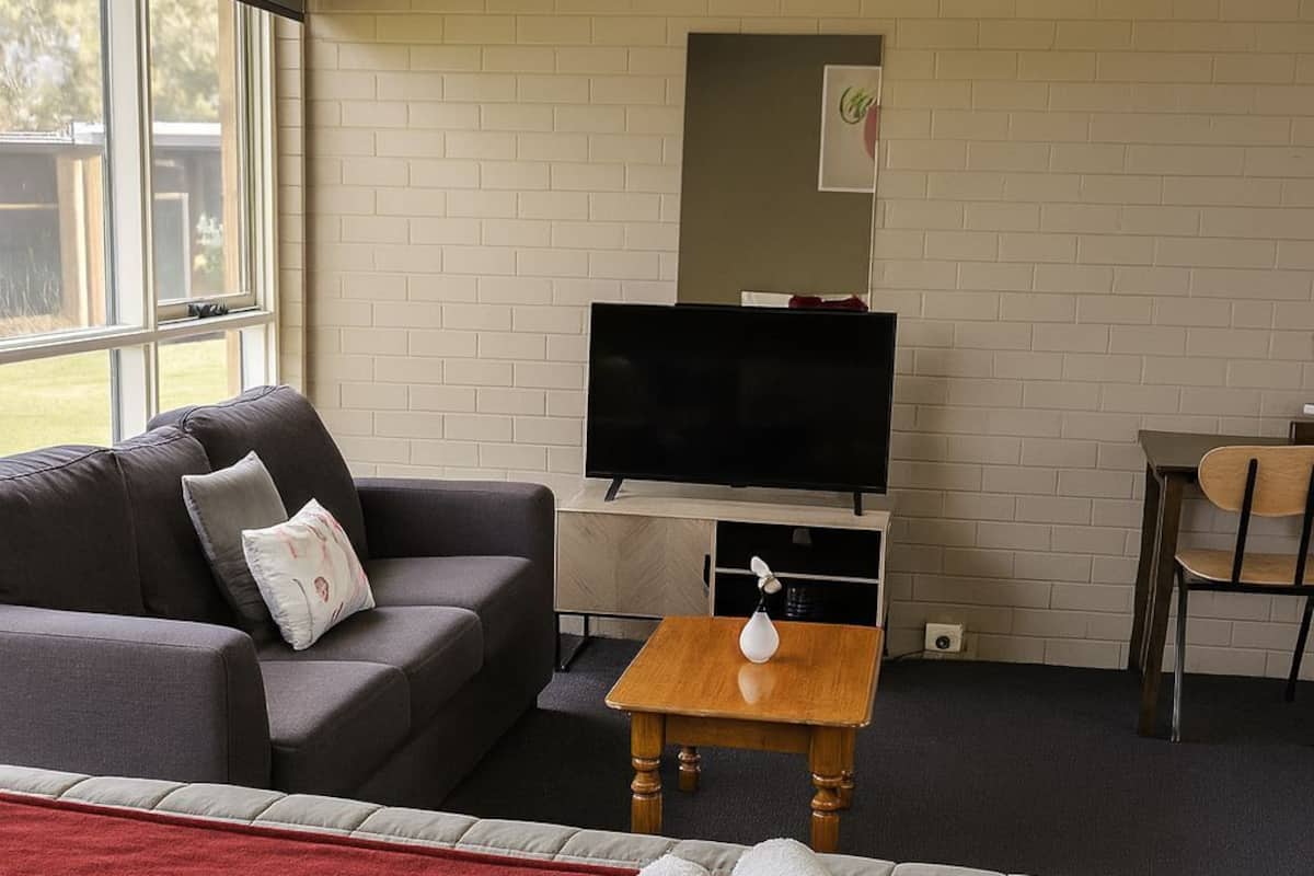 A hotel room with a bed, a sofa, a TV, and a small table.