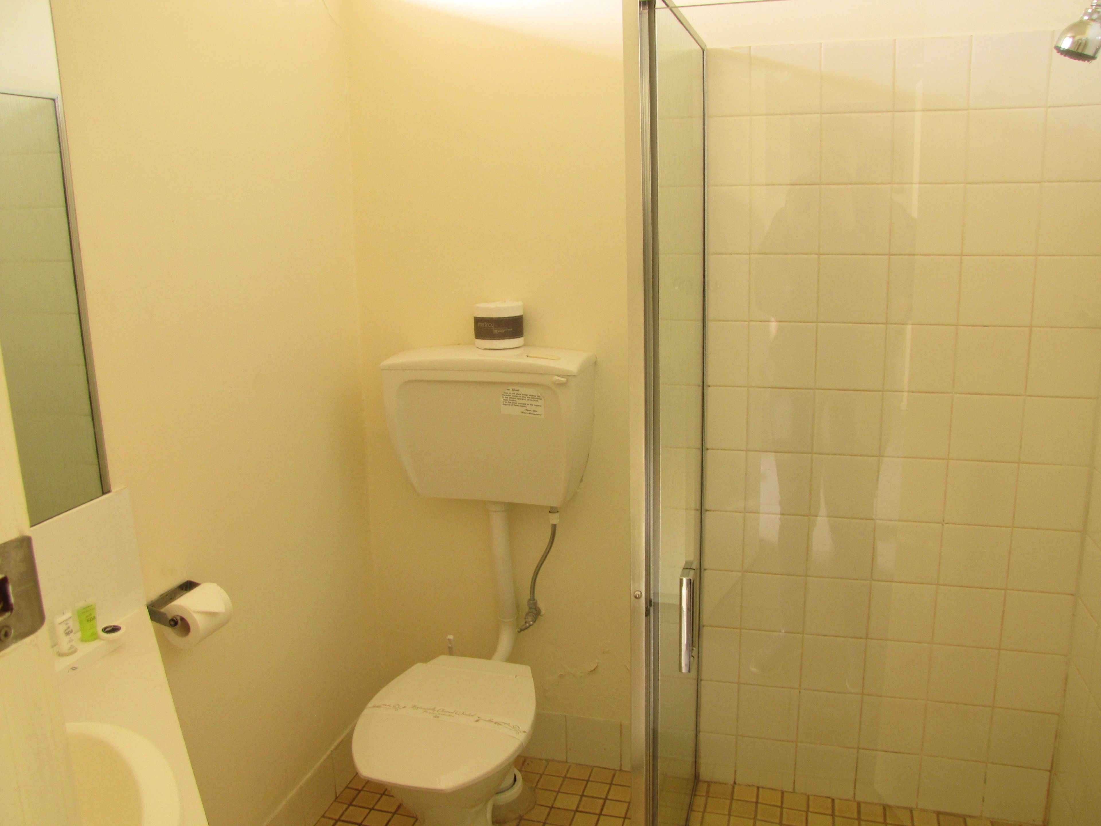 Une salle de bain avec des toilettes, une douche et une porte en verre.