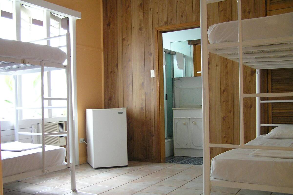 Une chambre avec des lits superposés, un réfrigérateur et une fenêtre.