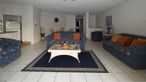 Ein Wohnzimmer mit Deckenventilator, zwei Sofas, einem Couchtisch und einem gemusterten Teppich.
