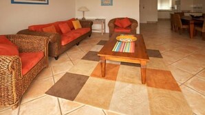 Ein Wohnzimmer mit Rattanmöbeln, einem Holztisch und einem Fliesenboden.