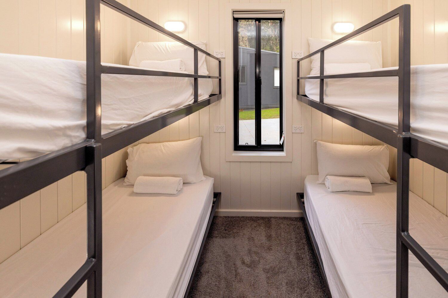 A compact room with bunk beds, a small window, and a carpeted floor.