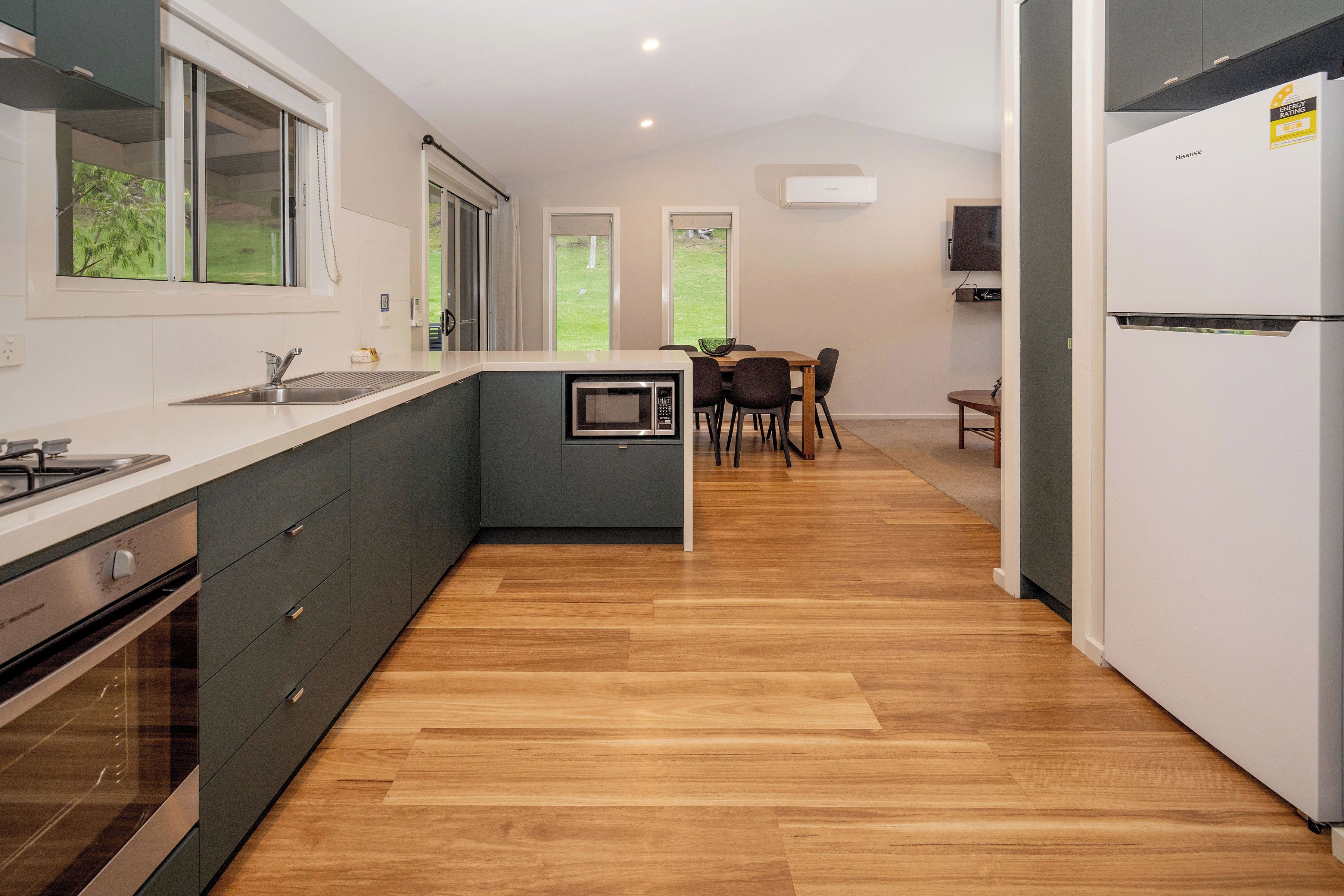 A modern kitchen with a built-in microwave, a sink, and a stove. There is a dining area with a table and chairs.