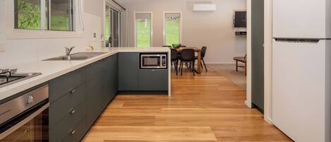 A modern kitchen with a built-in microwave, a sink, and a stove. There is a dining area with a table and chairs.