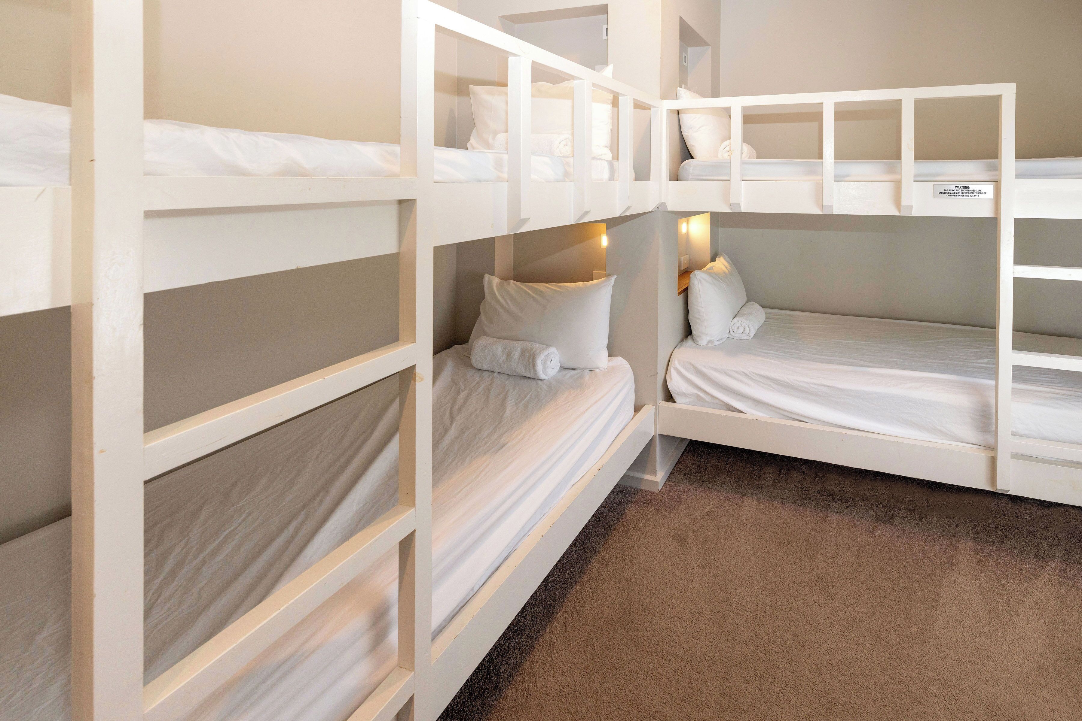 A bunk bed room with white bedding and a brown carpet.