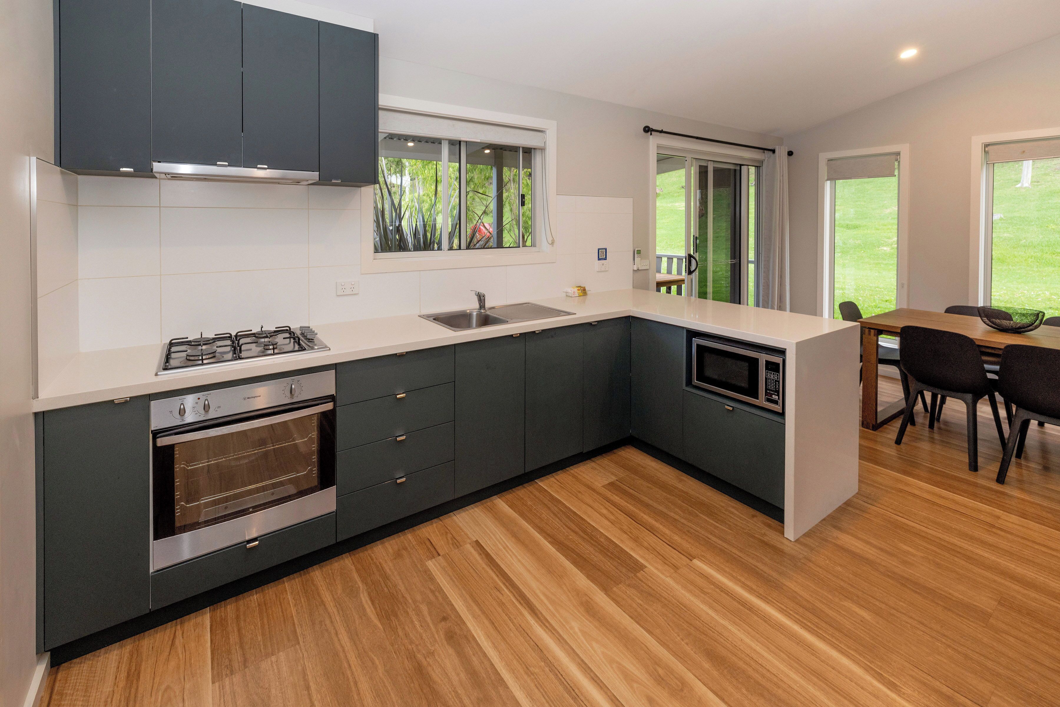 A modern kitchen with dark cabinets, a stainless steel stove, and a microwave.