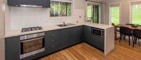 A modern kitchen with dark cabinets, a stainless steel stove, and a microwave.