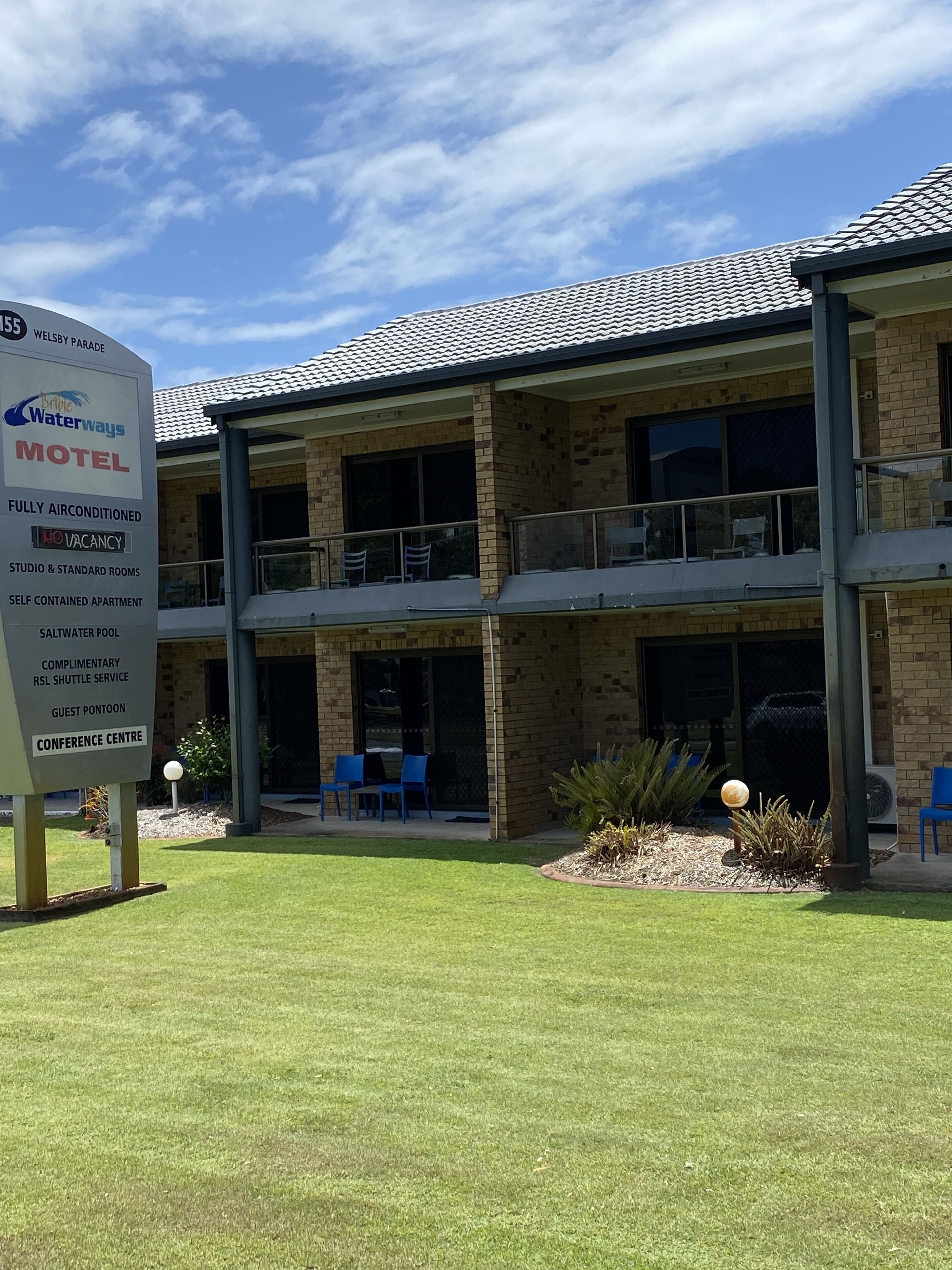 A motel with a sign listing amenities such as fully airconditioned rooms, a saltwater pool, and a conference center.
