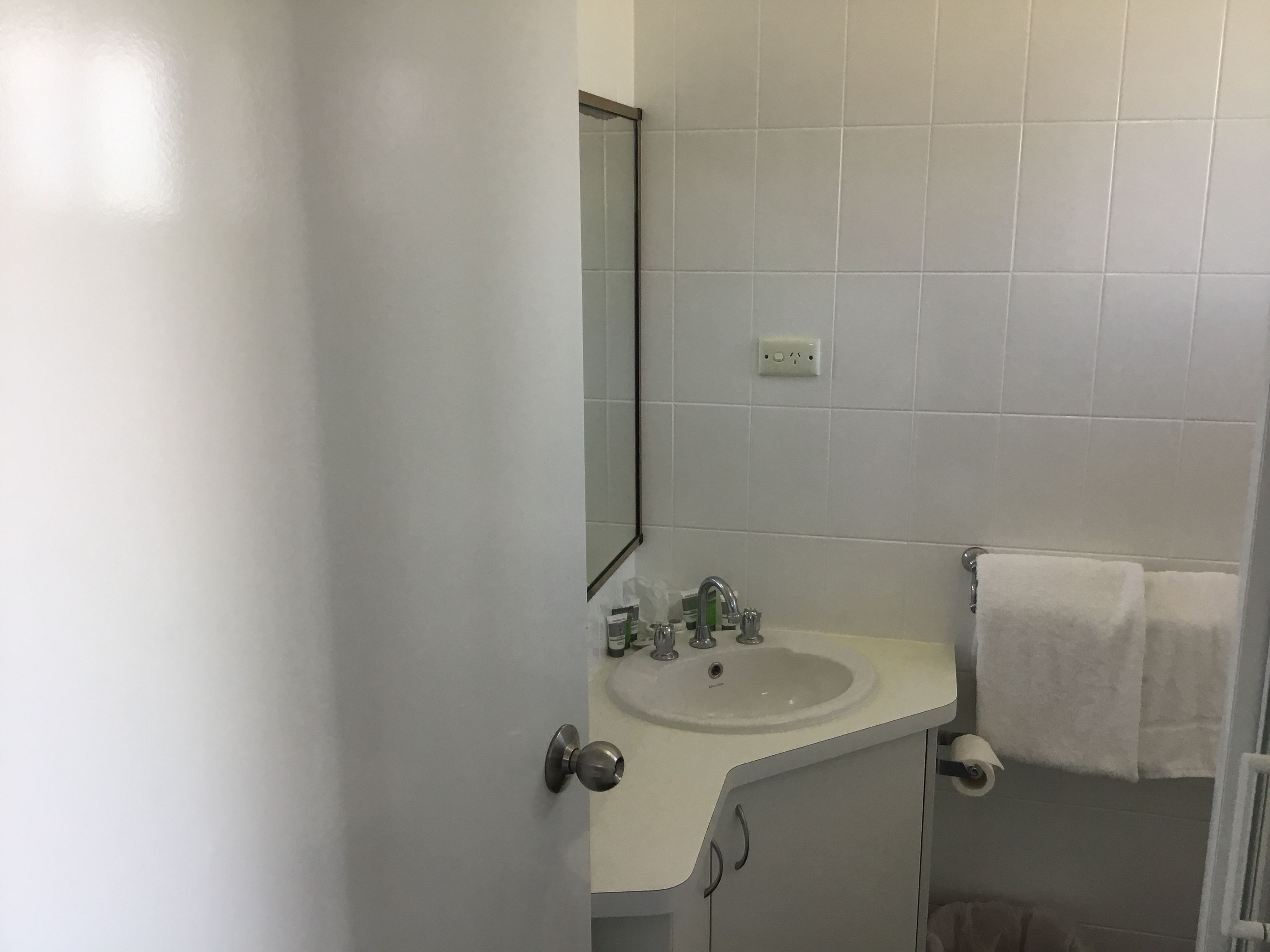 A bathroom with a white sink, mirror, and towel rack.