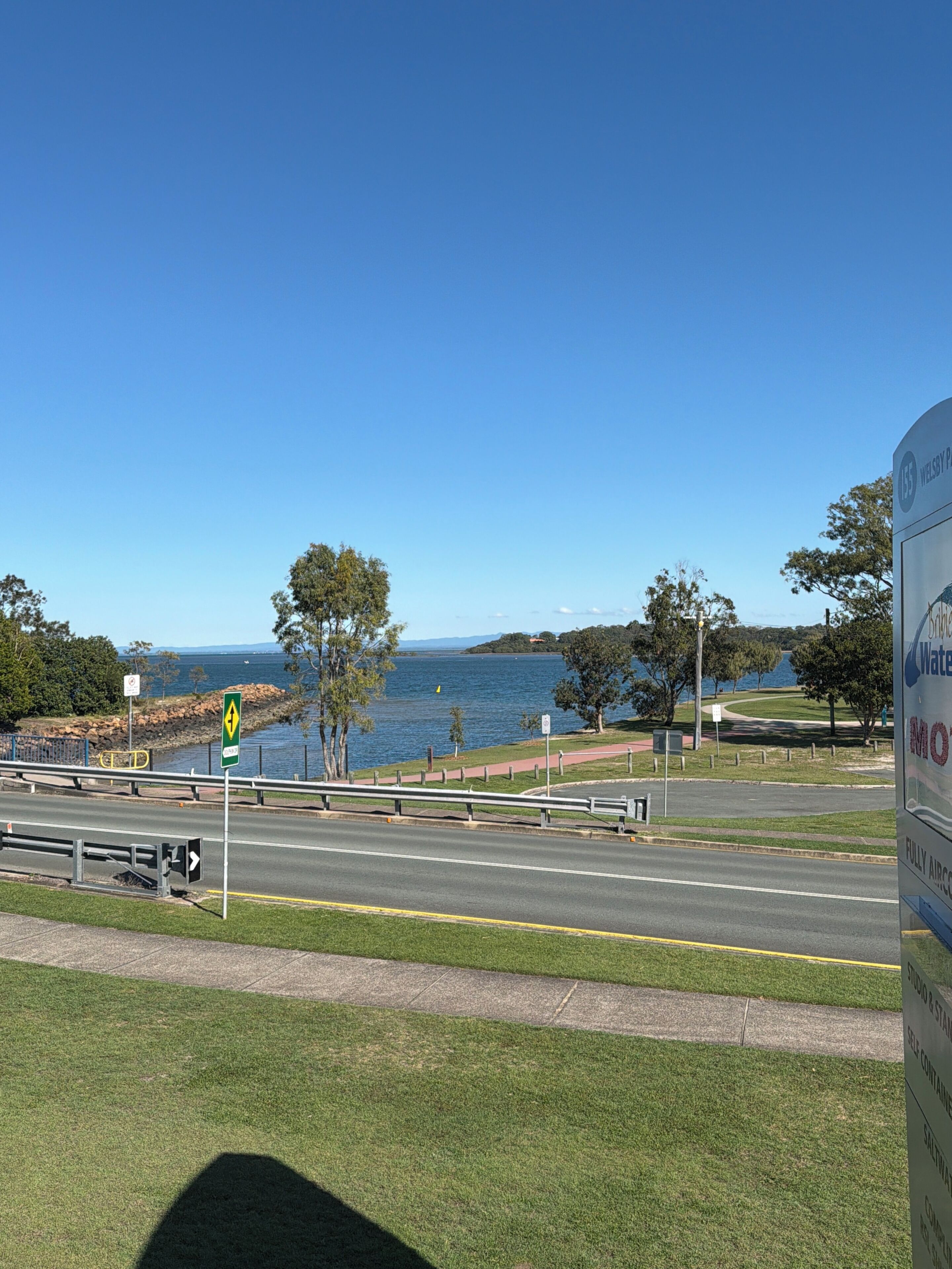 A coastal road with a sign for 'WELSBY PARK' and a view of the sea.