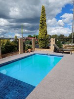 Una piscina al aire libre, sillones reclinables de piscina