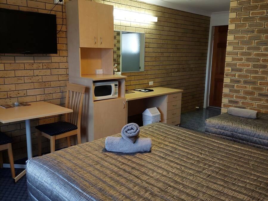 Una habitación de hotel con dos camas, un escritorio, una silla, un televisor y un microondas.