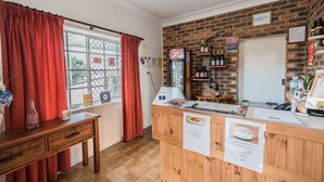 A reception area with a wooden desk, red curtains, a brick wall, and a Coca-Cola refrigerator.