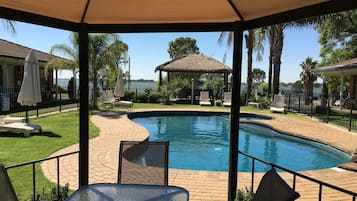 Una piscina al aire libre, sillones reclinables de piscina