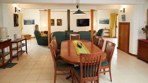 A dining area with a wooden table and chairs, a sofa, and a television mounted on the wall. - A View of Mt Warning B&B (Dum Dum)