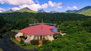 A house with a red roof, surrounded by lush greenery and mountains in the background. - A View of Mt Warning B&B (Dum Dum)