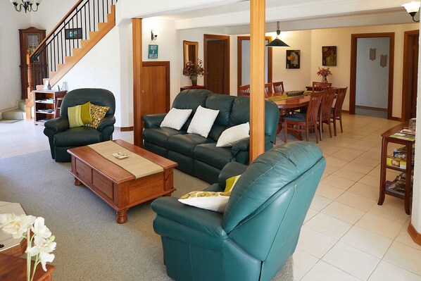 A spacious living room with a staircase, a dining area, and a bookshelf. - A View of Mt Warning B&B (Dum Dum)