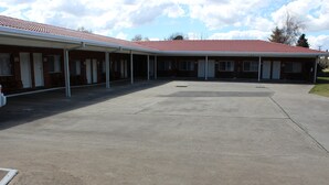 A motel with a covered parking area and multiple rooms.