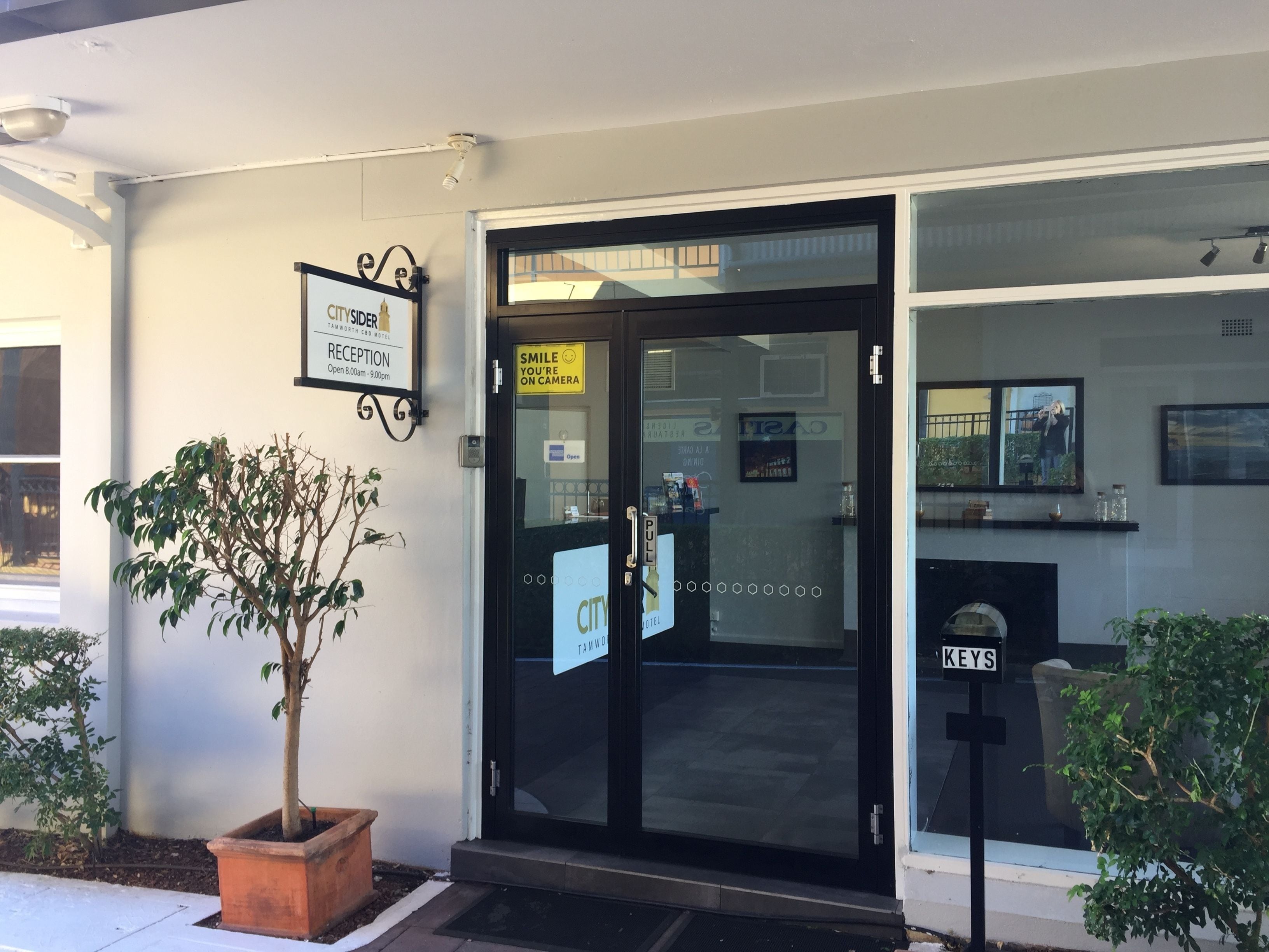 A hotel entrance with a reception desk, a sign indicating it's a CitySide Tamworth hotel, and a sign for keys.