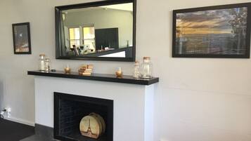 A room with a fireplace, a large mirror, and two framed pictures on the wall.