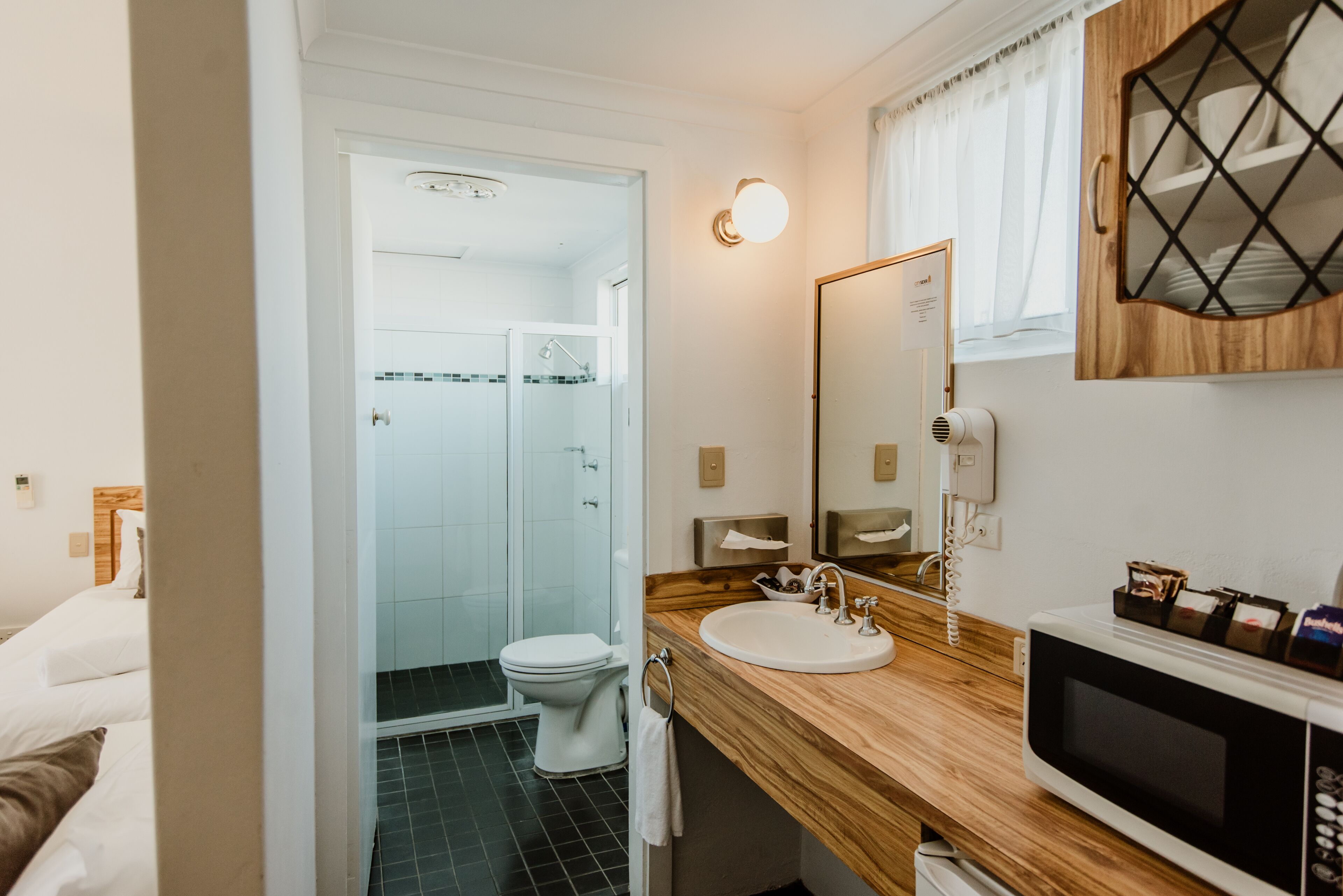 A bathroom with a wooden vanity, a white sink, a mirror, a toilet, and a shower area.
