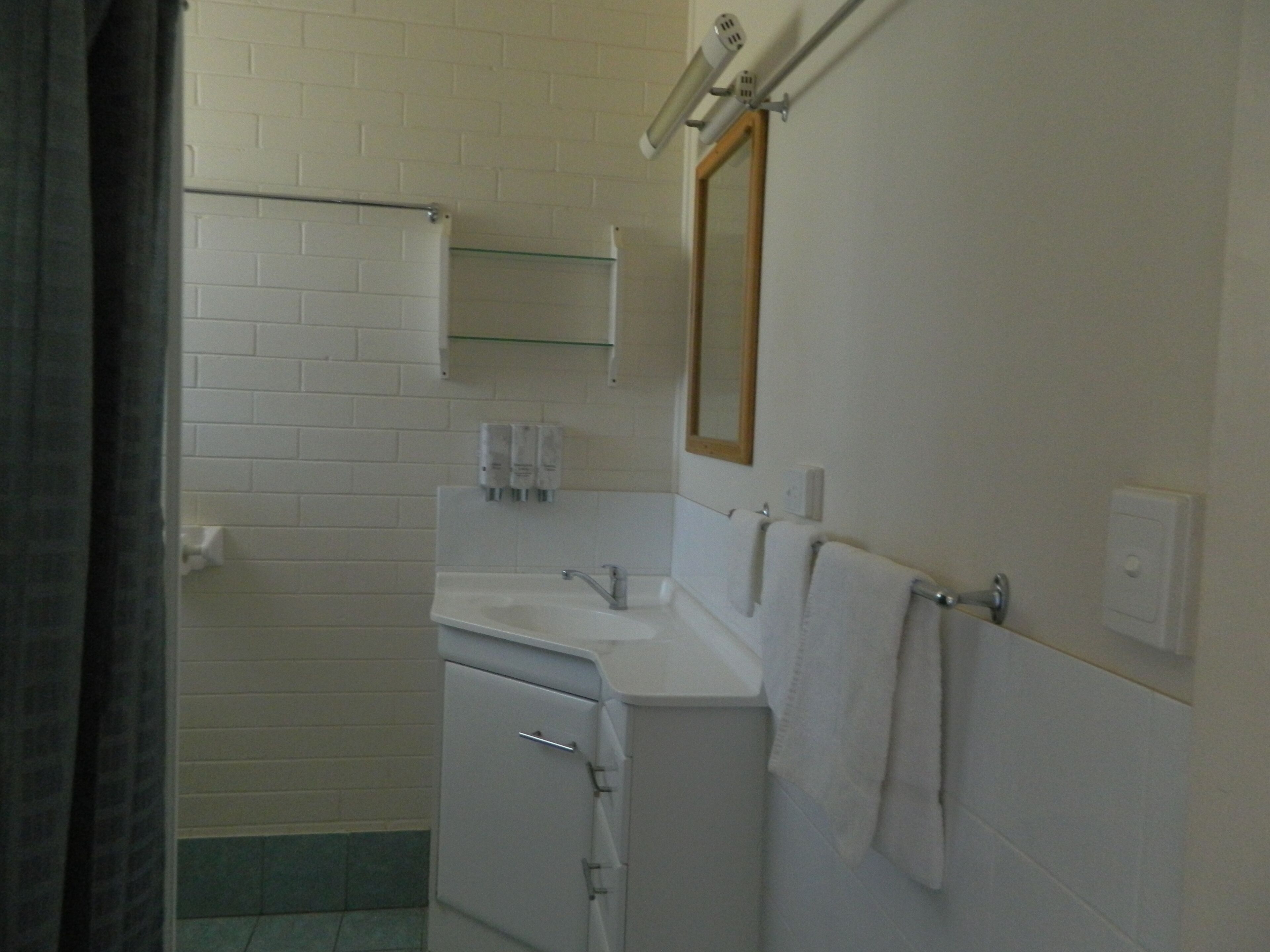Une salle de bain avec un lavabo blanc, un miroir et un porte-serviettes.