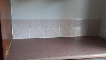 Una cocina con un microondas en un estante, una encimera marrón y un refrigerador con etiqueta de eficiencia energética.