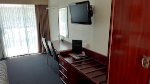 Habitación de hotel con escritorio de madera, televisor de pantalla plana, una silla y una cama.