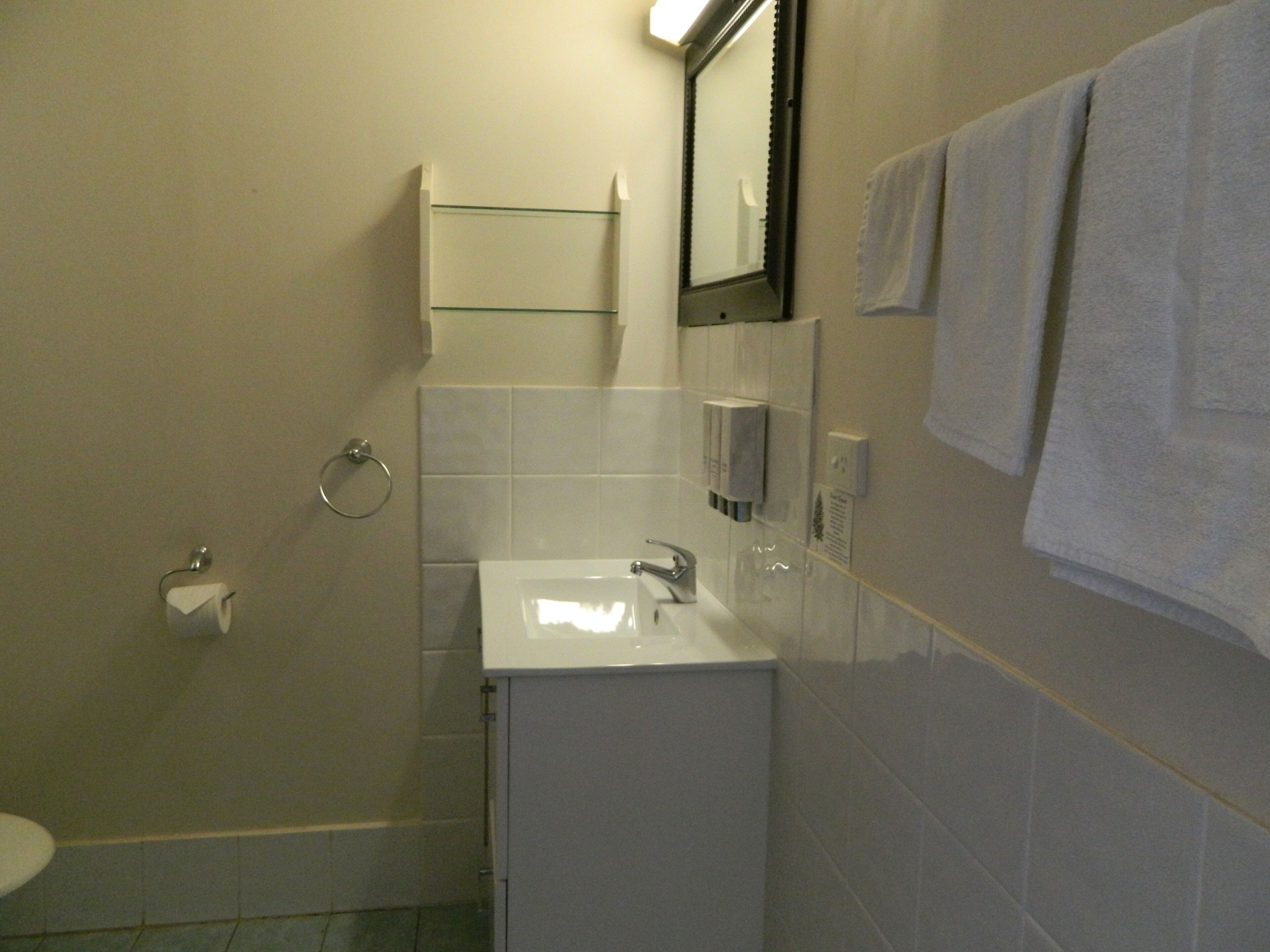 A small bathroom with a white sink, a mirror, a towel rack, and a toilet.