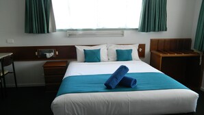 Una habitación de hotel con una cama, un escritorio y una silla.