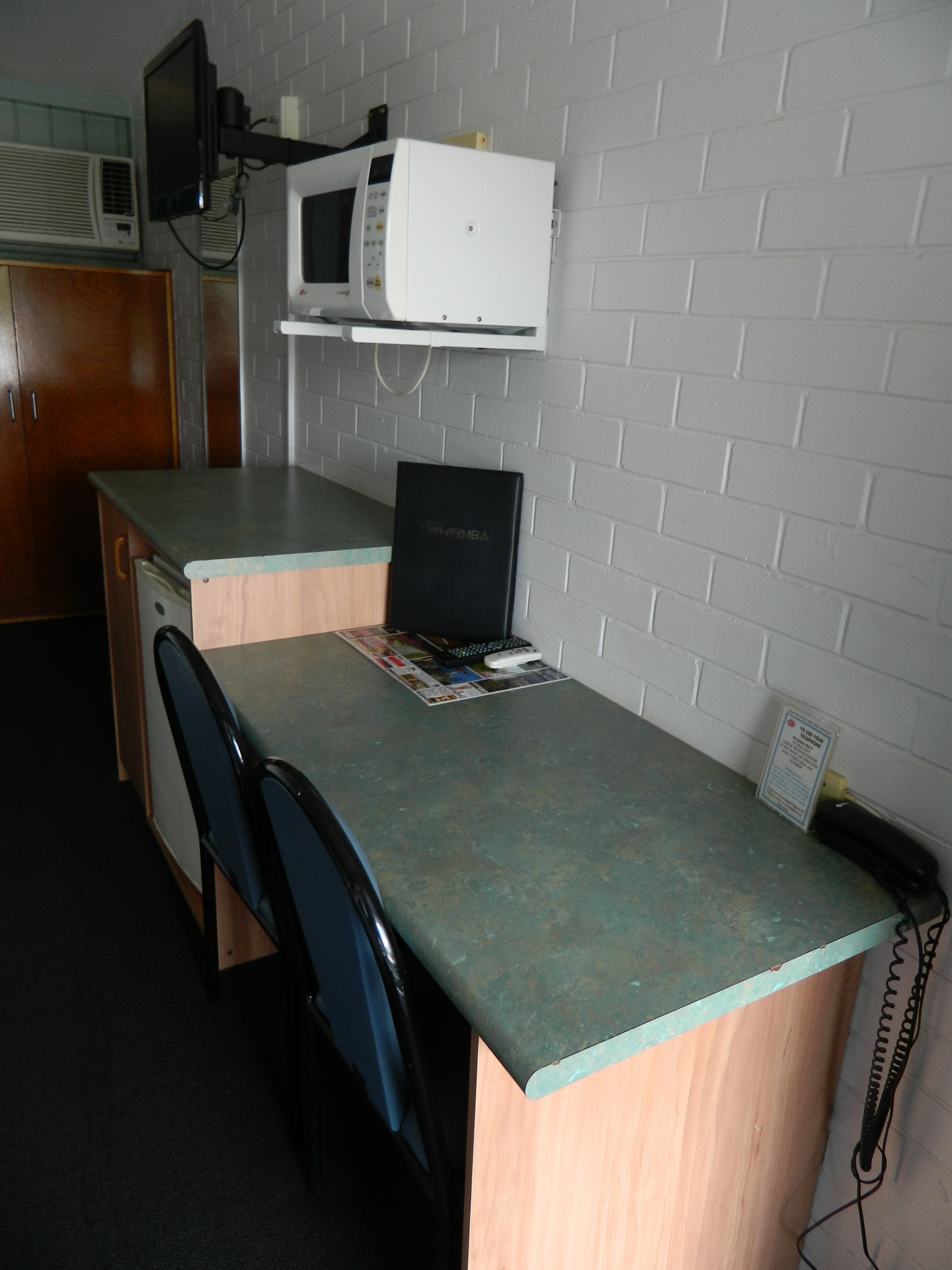 A compact kitchenette with a microwave, a small refrigerator, and a wooden cabinet.