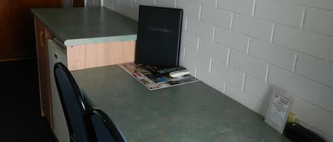 Una kitchenette compacta con microondas, un refrigerador pequeño y un armario de madera.