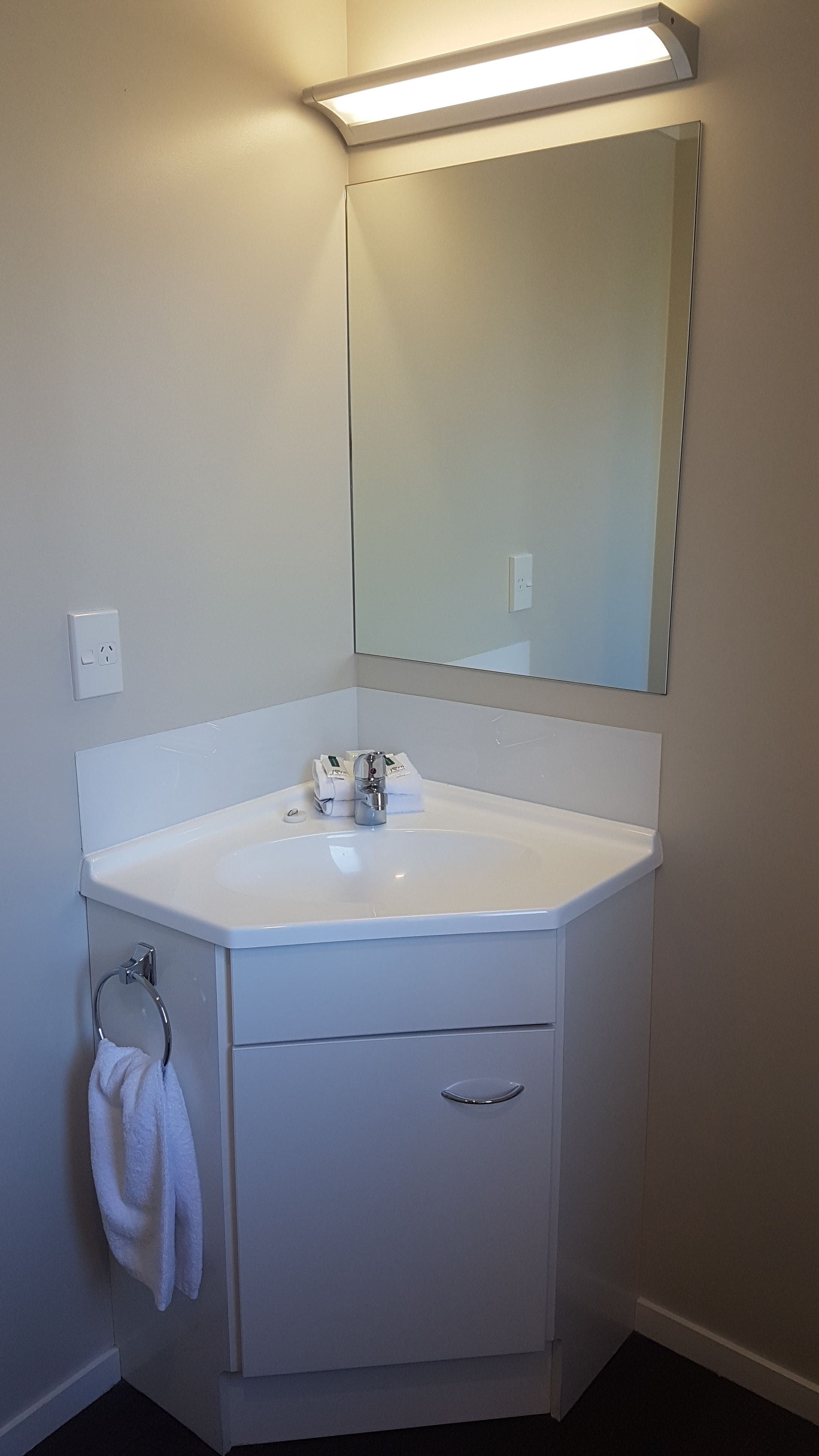 A bathroom with a white sink, a mirror, and a towel rack.