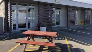 A building with a parking area, a picnic table, and a potted plant. - Aspree Motor Inn (Palmerston North)