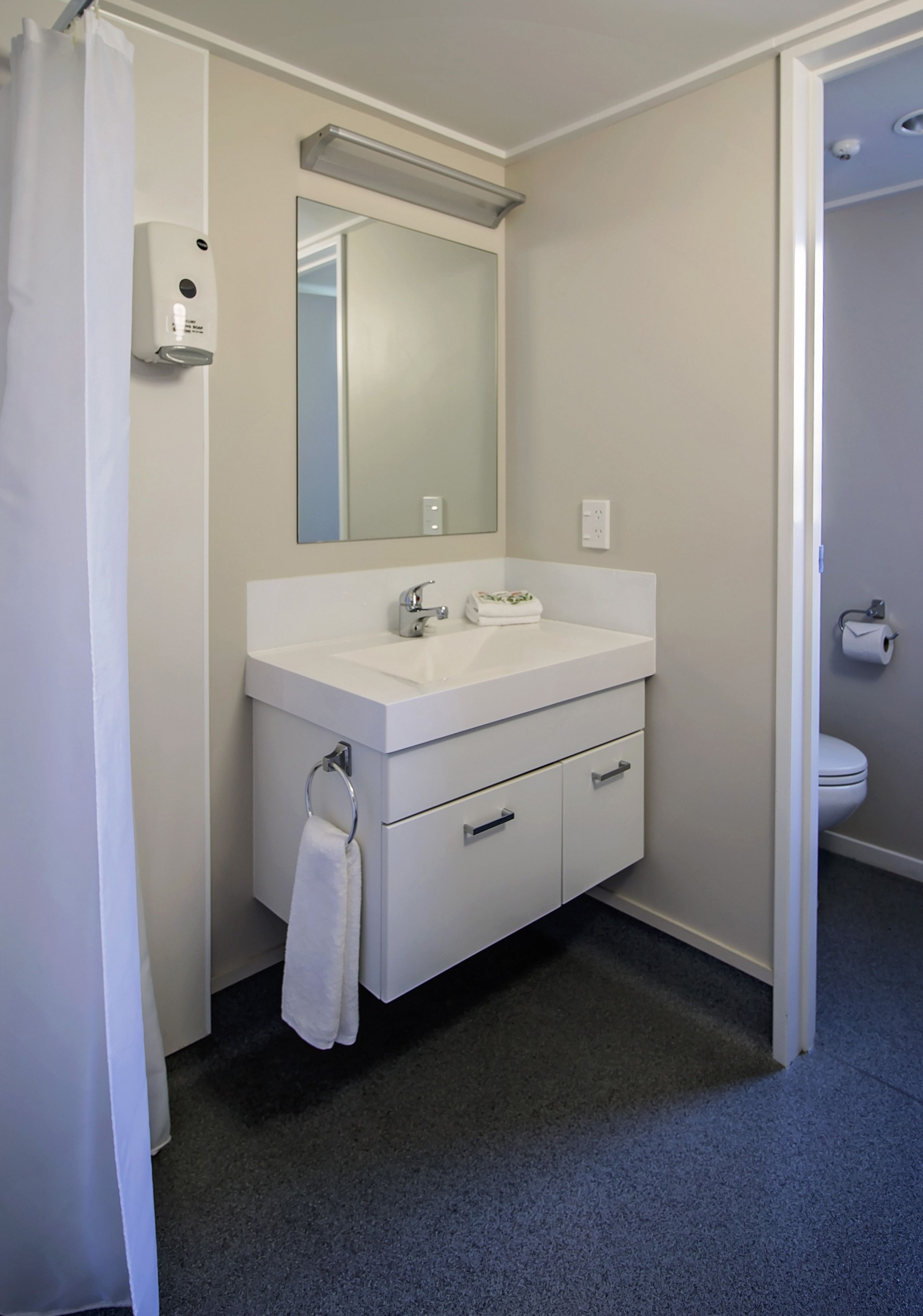 Un baño con lavamanos, espejo y retrete blanco.