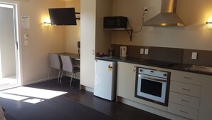 A compact kitchenette with a microwave, oven, and a small refrigerator. There is a seating area with two chairs and a table. - Aspree Motor Inn (Palmerston North)