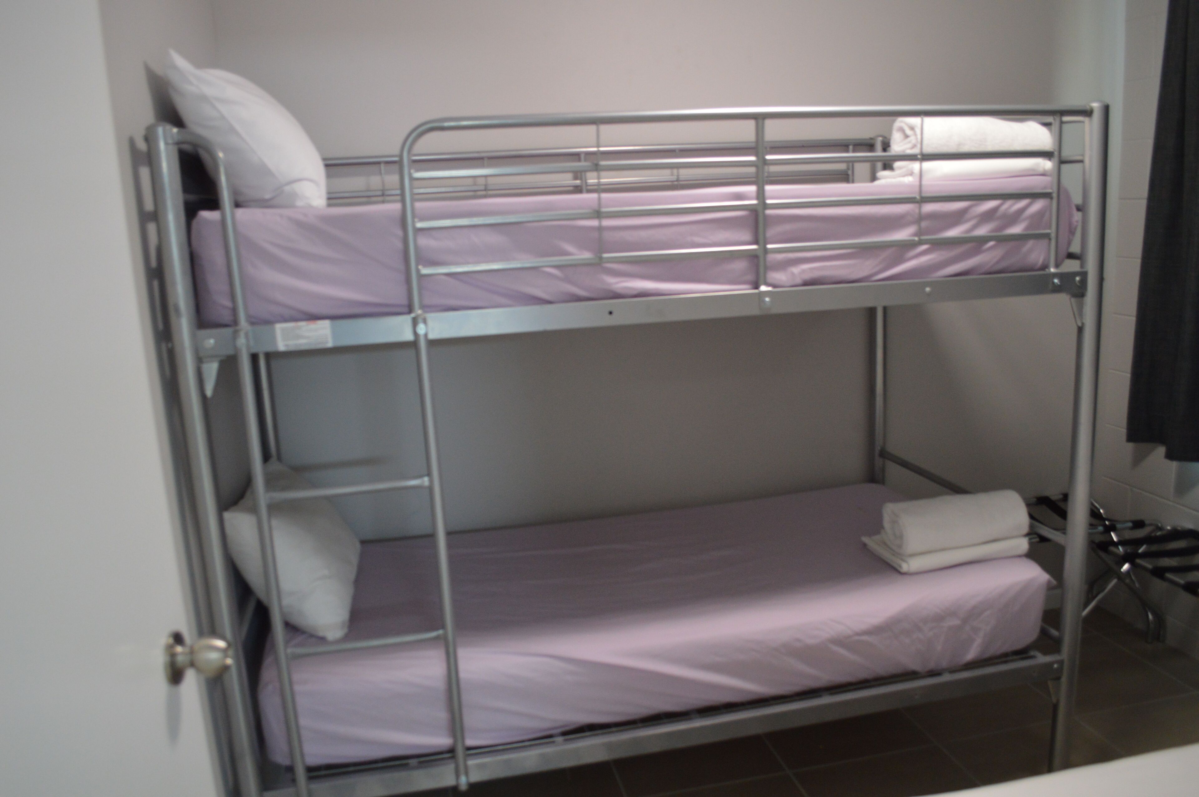A bunk bed with two levels, each with a pillow and a folded towel.