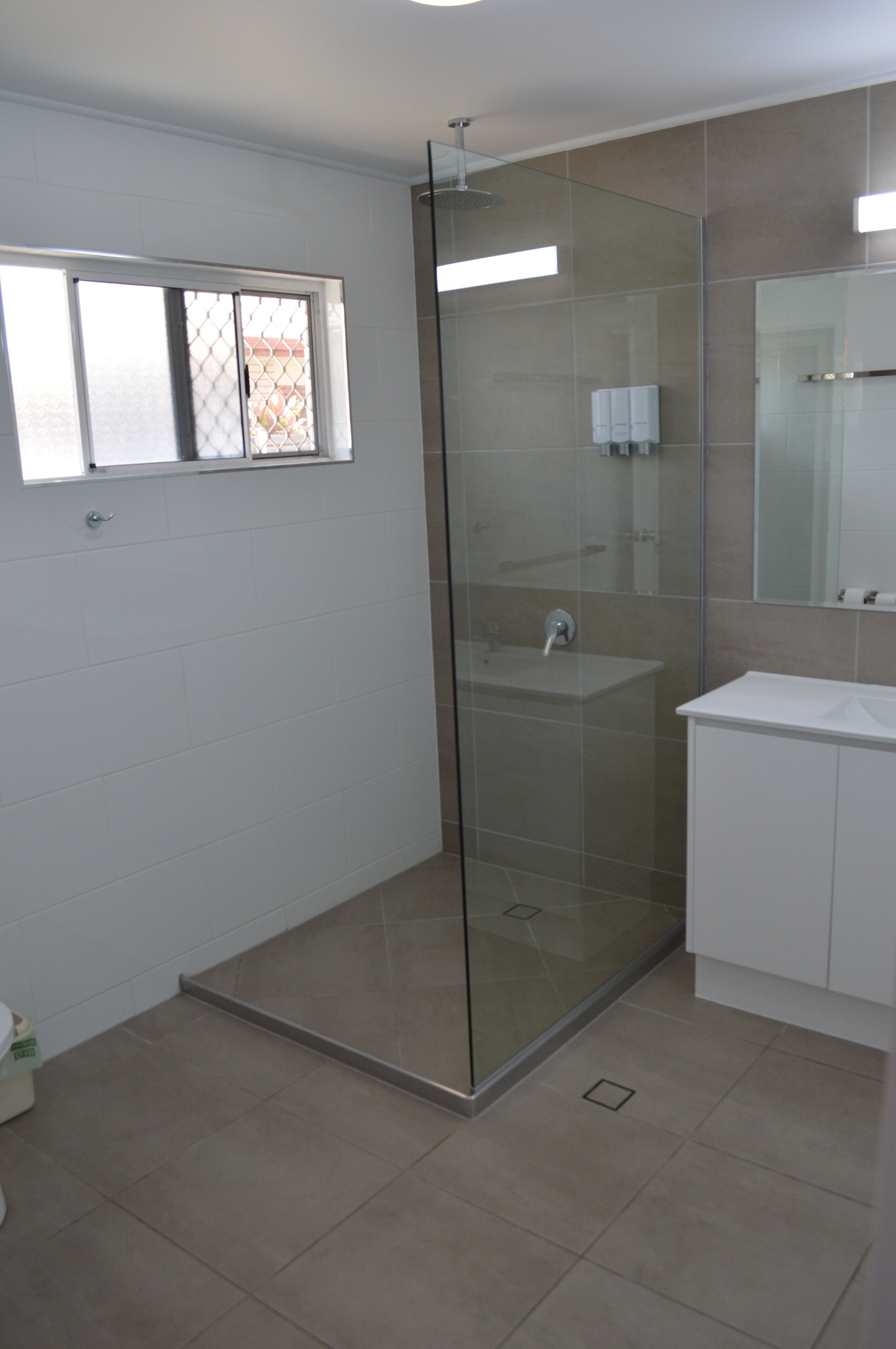 A modern bathroom with a glass-enclosed shower, a white sink, and a mirror above the sink.