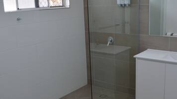 A modern bathroom with a glass-enclosed shower, a white sink, and a mirror above the sink.