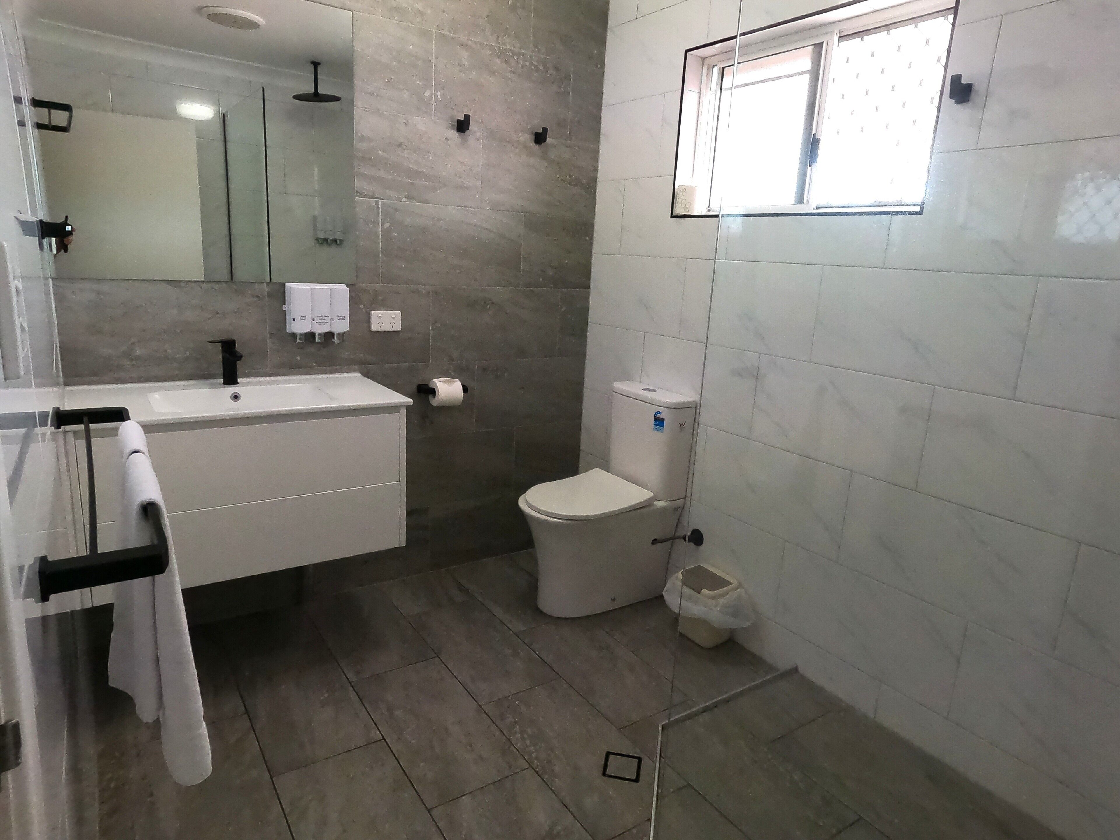 A modern bathroom with a white sink, mirror, and toilet.