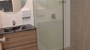 A modern bathroom with a glass shower enclosure, a wooden vanity with a sink, and a mirror above it.