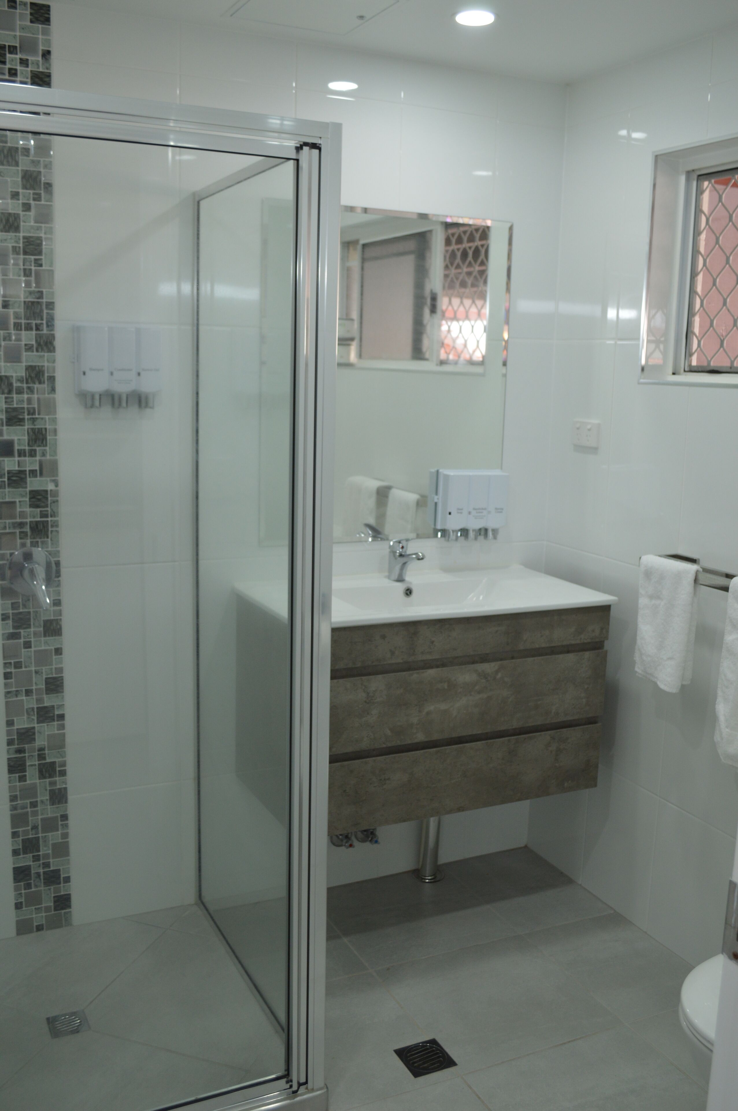 Un bagno moderno con doccia vetrata, un lavandino bianco con specchio sopra e un water.