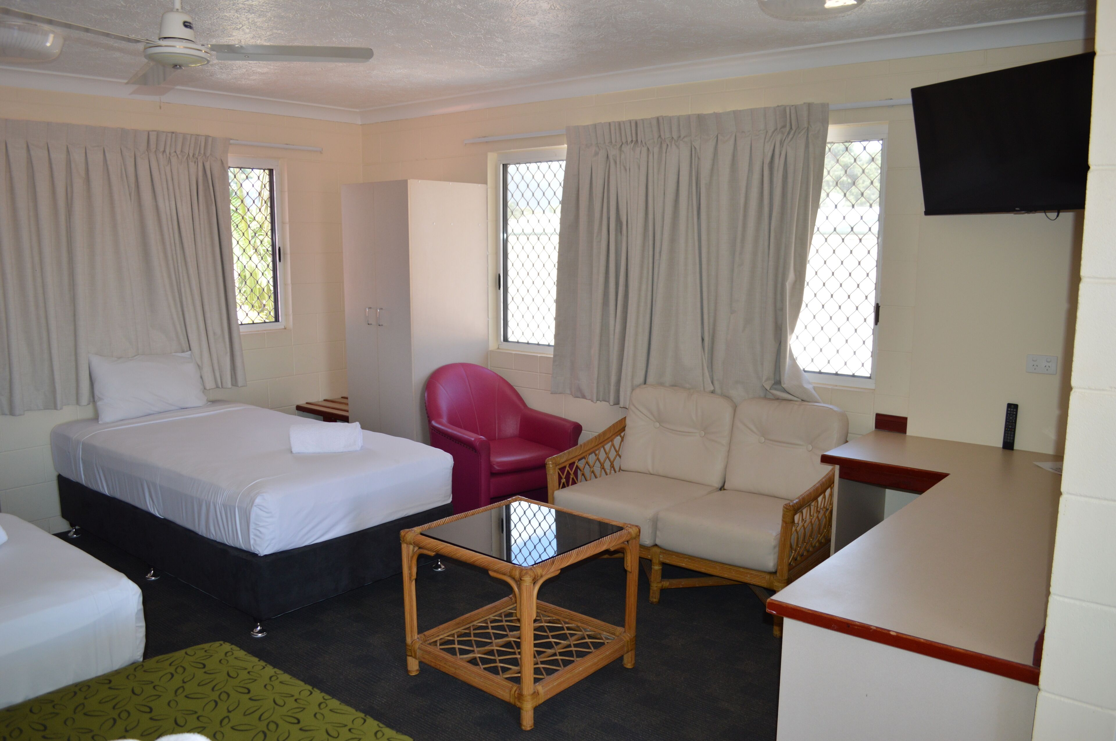 A hotel room with a bed, a sofa, a small table, and a TV.