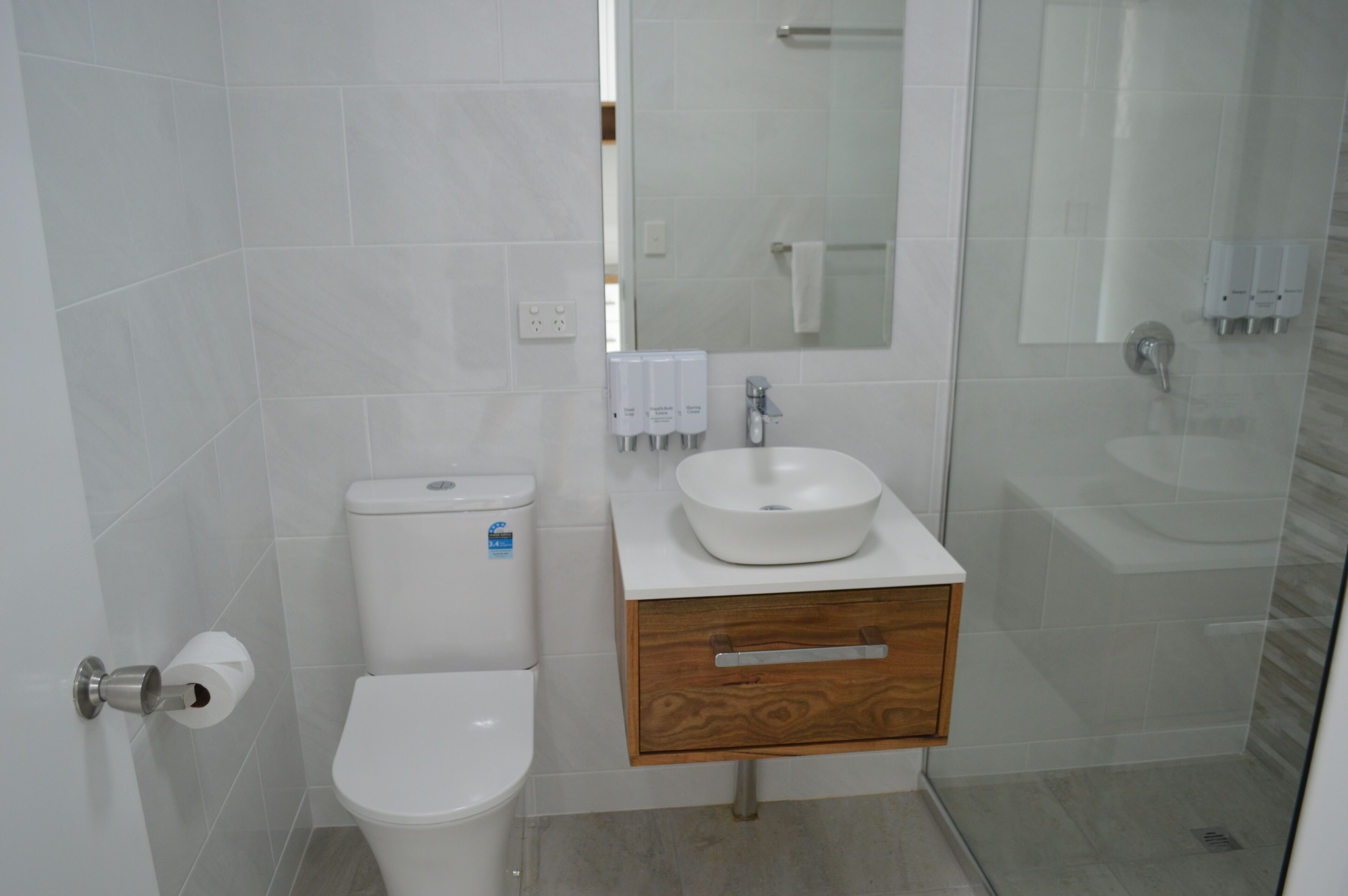 A modern bathroom with a toilet, sink, and glass shower enclosure.