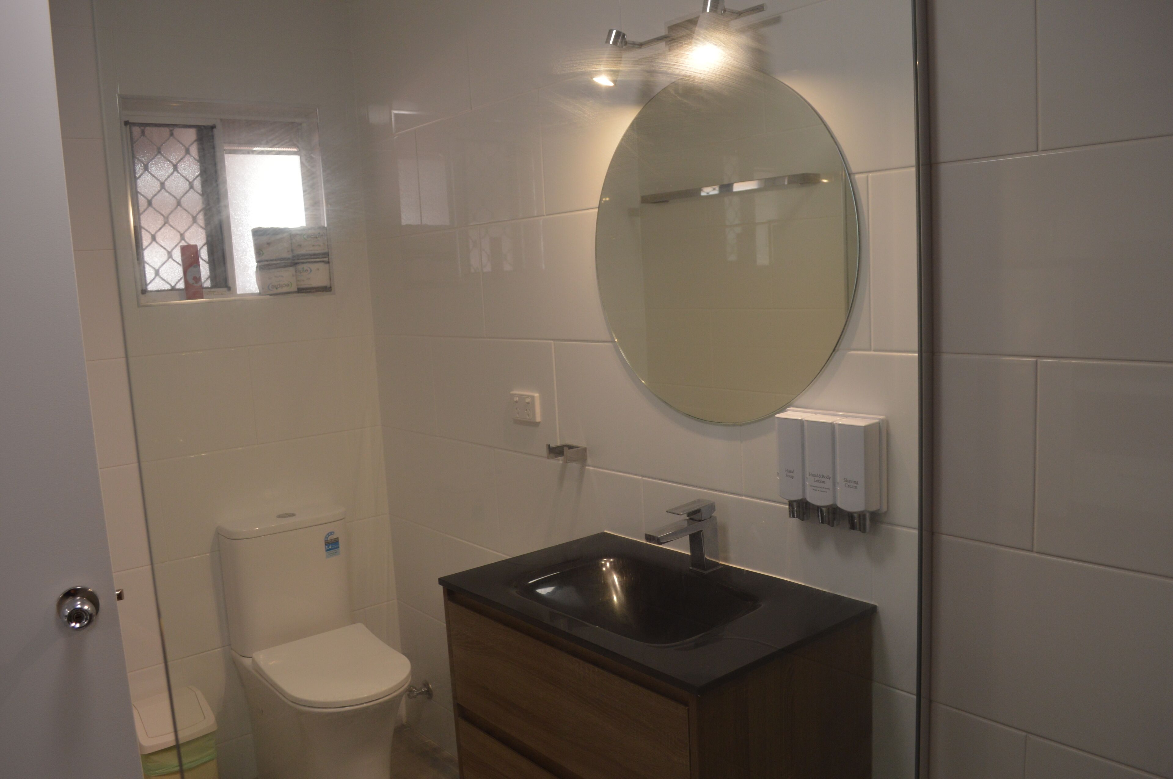 Ein Badezimmer mit Toilette, Waschbecken mit Spiegel und einem Fenster mit Aussicht.