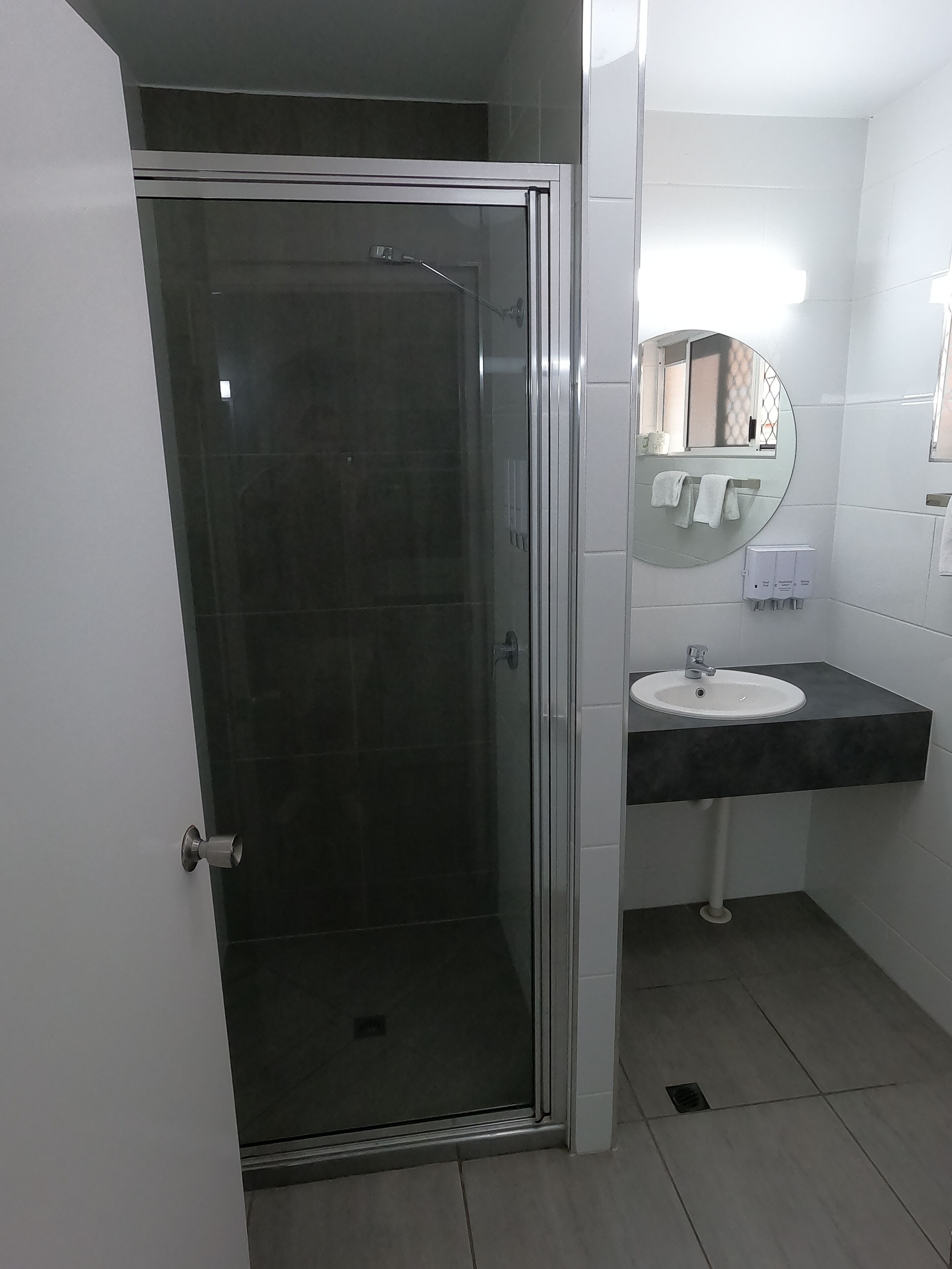 A bathroom with a glass-enclosed shower, a white sink, and a mirror above the sink.